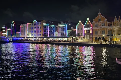 De verlichte gevels van de Handelskade in Willemstad bij nacht