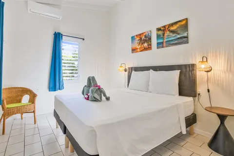 Slaapkamer 1 met rieten stoel en wandkunst