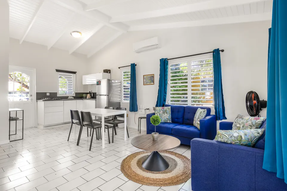 Woonkamer met twee blauwe banken, eettafel en open keuken